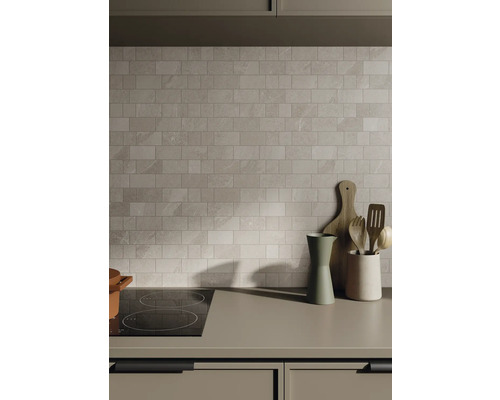 Scenă de bucătărie cu perete de faianță, plită și ustensile de bucătărie pe blat.