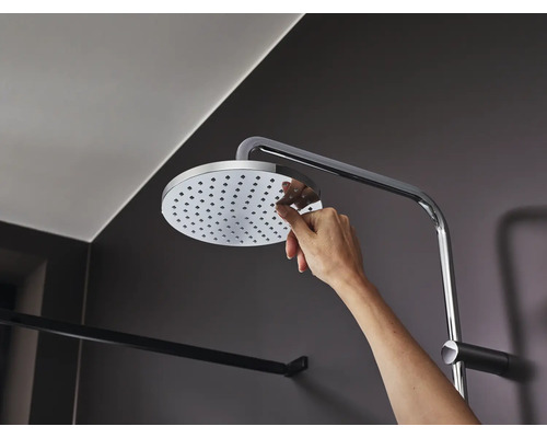 Mână atingând capul de duș cu brațul de duș în baie