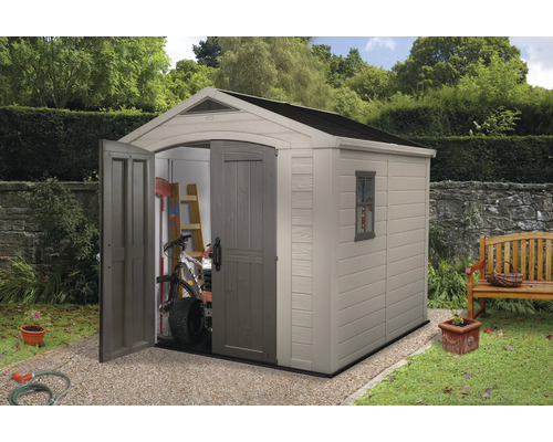 Șopron de grădină cu ușa deschisă, în care se află o bicicletă și unelte de grădină.