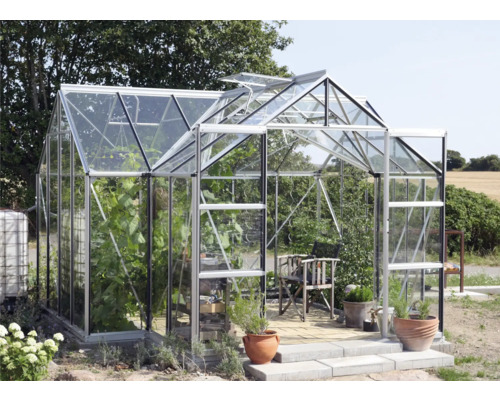 Seră cu plante, scaun și ghivece în grădină