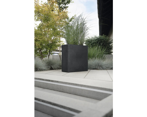 Jardinieră pătrată din piatră cu plante în exterior.