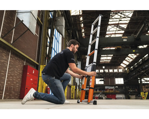 O persoană reglează o scară telescopică din aluminiu într-un depozit.