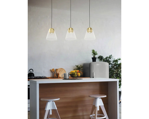 Trei corpuri de iluminat suspendate din sticlă și metal deasupra unui blat de bucătărie cu scaune de bar