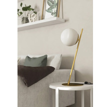 Scenă decorativă cu lampă de masă, canapea, perne, pătură și raft de perete