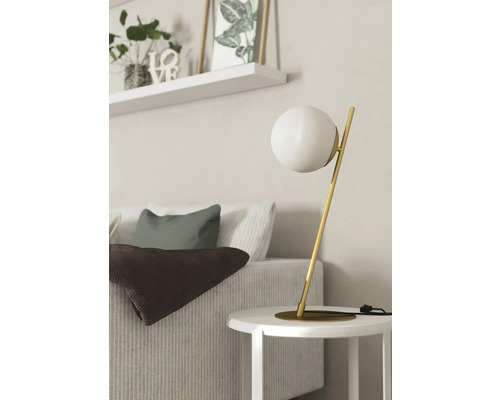 Scenă decorativă cu lampă de masă, canapea, perne, pătură și raft de perete