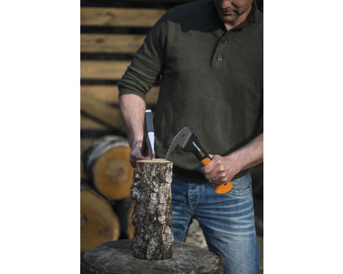 Bărbat despărțind lemn cu un ciocan de despicat și o pană pe un butuc