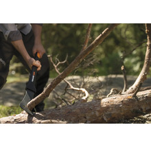 O persoană folosește un topor Fiskars pentru a despica un trunchi de copac.