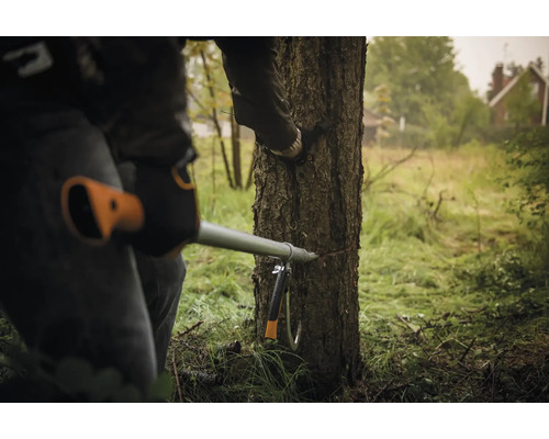 Persoană taie un copac cu un ferăstrău de tăiat crengi.