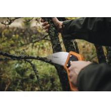 Prim-plan cu o persoană care taie o ramură cu un fierăstrău manual Fiskars.