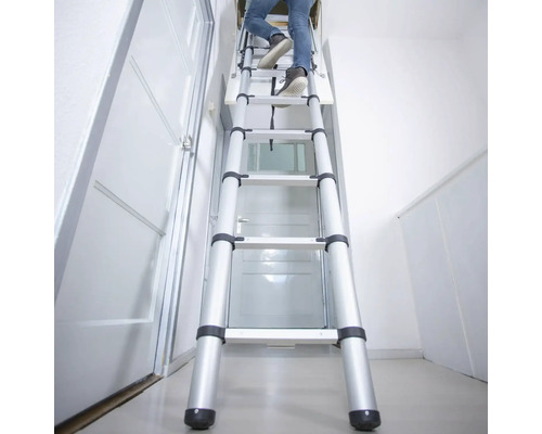 Persoană care urcă pe o scară de mansardă telescopică din aluminiu într-o casă
