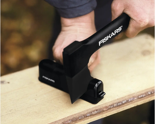 Logo Fiskars pe un topor cu protecție pentru lamă pe o bucată de lemn