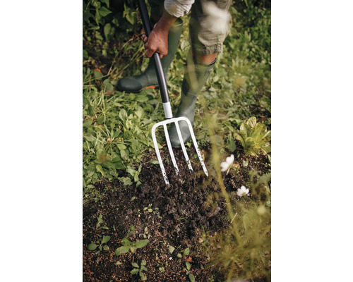 O persoană folosește o furcă de săpat pentru a lucra în grădină.