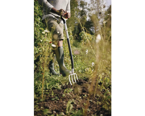 Grădinar care folosește o furcă pentru a săpa pământul din grădină.