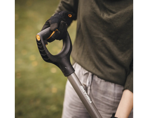 O persoană ține o sapă marca Fiskars.