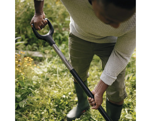 O persoană sapă în grădină cu o cazma marca Fiskars.