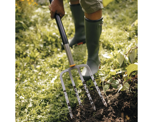 O persoană folosește o furcă de grădină în grădină.