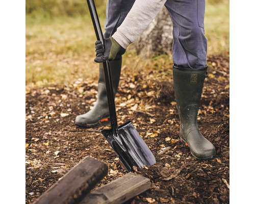 Persoană înfigând o sapă în pământul de grădină lângă bucăți de lemn