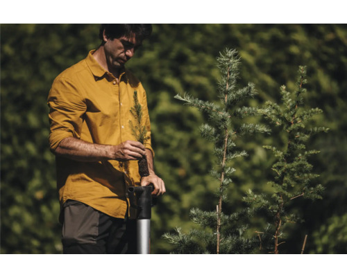 O persoană plantează un copac tânăr cu un instrument de plantare.