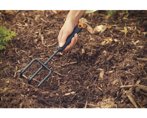 Persoană care lucrează cu un cultivator în solul din grădină.