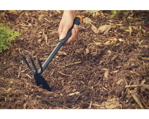 Persoană care folosește o sapă de grădină pentru a plivi într-o grădină.