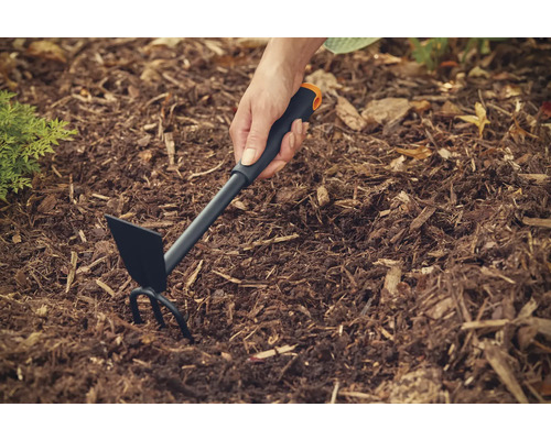 Săpăligă de grădină utilizată pe un strat de flori cu mulci de scoarță