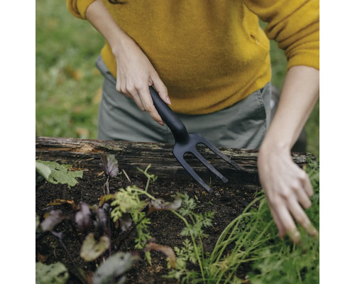 O persoană care folosește o gheară de grădină într-o grădină supraînălțată
