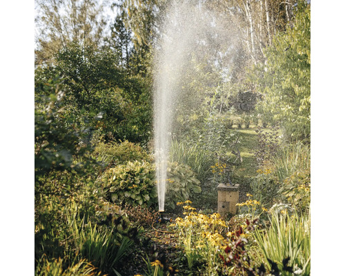 Irigarea grădinii cu un aspersor de gazon printre plante