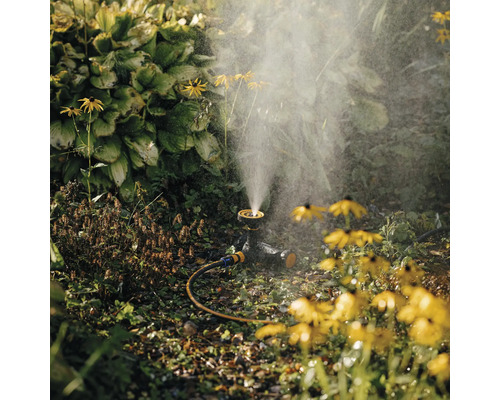 Scenă de grădină cu aspersor de gazon și flori galbene