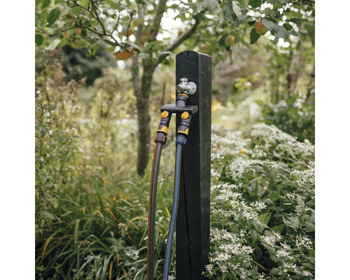 Stâlp de robinet de apă cu două furtunuri de grădină conectate în grădină.