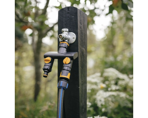 Robinet de apă cu distribuitor pe un stâlp de lemn în grădină