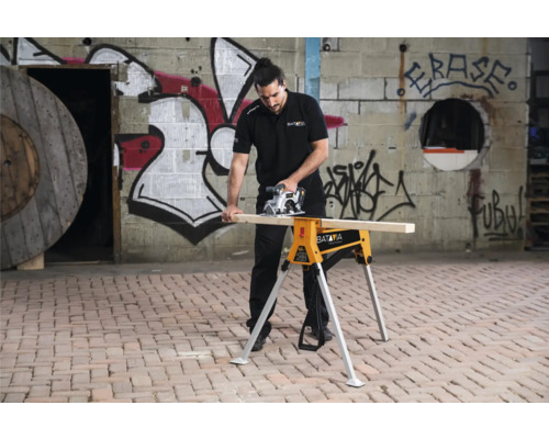 Bărbat taie lemn cu un ferăstrău circular manual pe un capră de tăiere