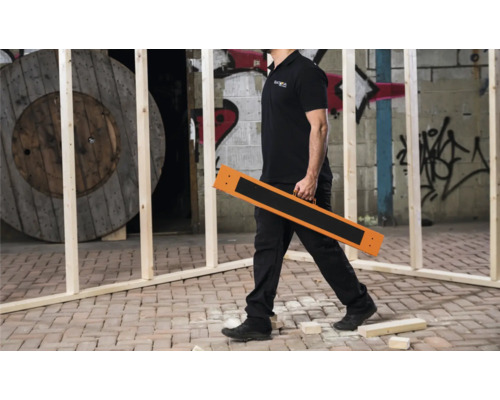 Un meșter transportă o saltea de protecție a podelei pe un șantier