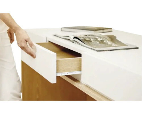 Persoană care deschide un sertar al unei mese. Pe masă sunt cărți.