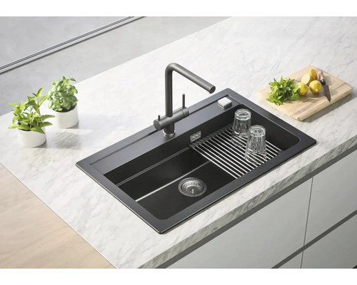 Chiuvetă de bucătărie întunecată cu suport pentru uscare și robinet pe un blat de bucătărie.