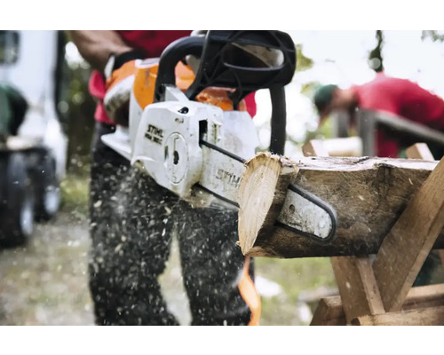 O persoană taie o bucată de lemn cu un motofierăstrău Stihl.