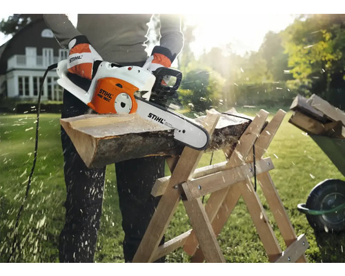O persoană taie lemne cu un fierăstrău electric cu lanț Stihl pe un capră de tăiat lemne