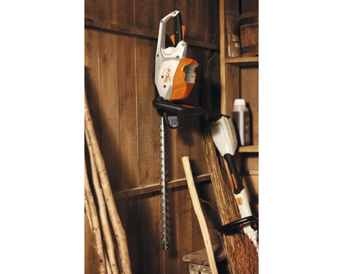 Foarfecă de gard viu fără fir Stihl pe un perete de lemn.