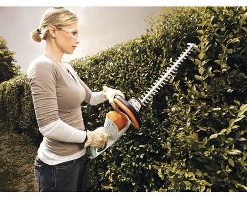 Femeie tăind gard viu cu foarfeca de gard viu