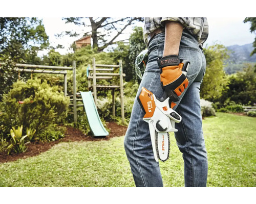 O persoană ține un motoferăstrău cu acumulator Stihl în grădină.