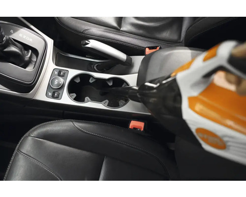 Un aspirator portabil este folosit în interiorul unui vehicul pentru a curăța un suport de pahare.