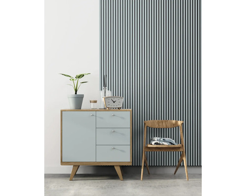 Scenă de interior cu comodă, scaun, ceas și plantă de interior în fața unui perete cu panouri cu lamele