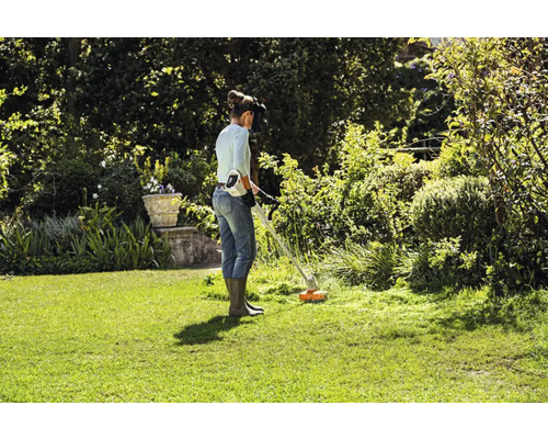Femeie lucrează cu o mașină de tuns iarba cu acumulatori în grădină