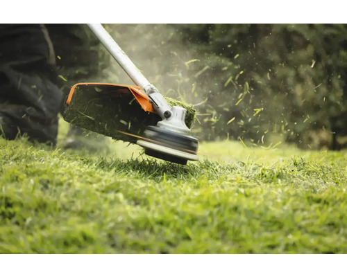 Trimmer de gazon în acțiune la tăierea ierbii