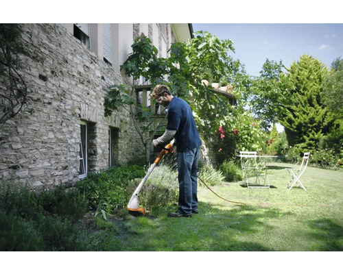 Un bărbat lucrează cu o mașină de tuns iarba în grădină.