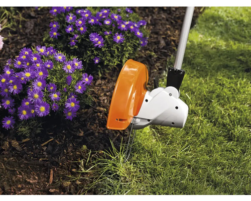 Trimmer de gazon într-o grădină cu flori și gazon