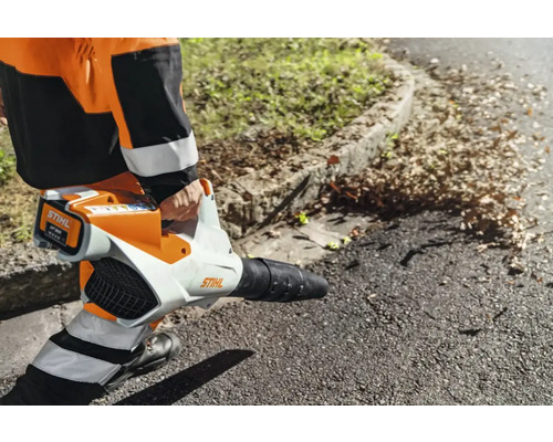 O persoană folosește o suflantă de frunze cu acumulator Stihl pentru a îndepărta frunzele.