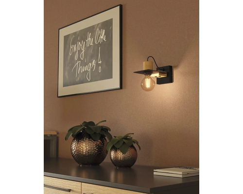 Lampa de perete din lemn și metal lângă o fotografie înrămată și două plante pe un dulap