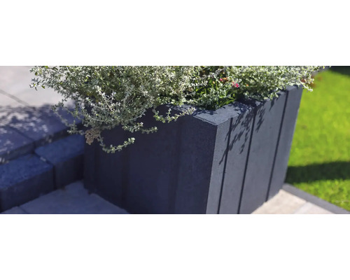 Un jardinière de beton cu plante pe o terasă.