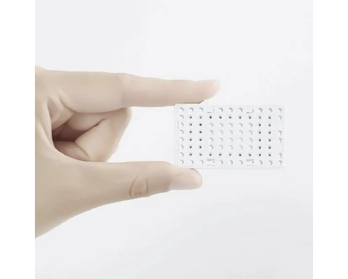 O mână ține o placă de test albă cu găuri.
