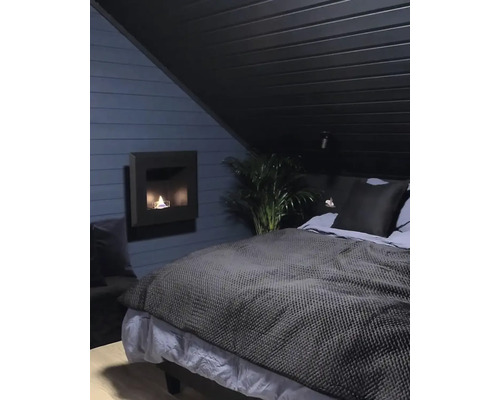 Dormitor cu pat dublu, șemineu cu etanol și plantă de interior sub un tavan înclinat.